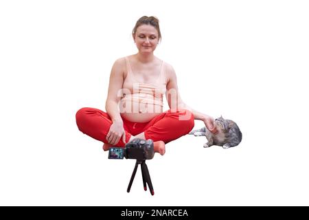 A pregnant woman is engaged in fitness and conducts classes online through the camera, isolated on a white background Stock Photo