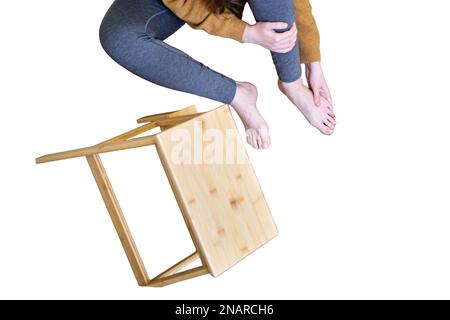 A man holds on to his injured leg after falling from a wooden ladder, isolated on a white background. Safety issues at work at height due to disruptio Stock Photo