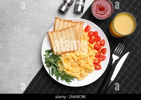 Delicious scrambled eggs served on light grey table, flat lay Stock Photo