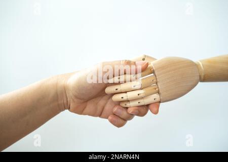 Business and Automation Concept. Closeup of woman hand make a hand shake with wooden hand on white back ground. Stock Photo