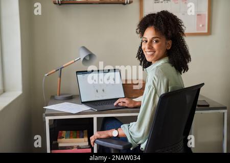 Smiling businesswoman working on a laptop in her home office Stock Photo
