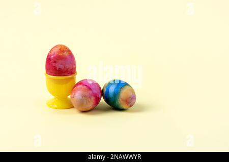 Three Easter multicolored eggs on a yellow background. Happy Easter concept. Greeting card. Stock Photo