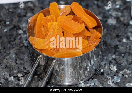 dried apricots in a metal cup on a granite surface. Stock Photo