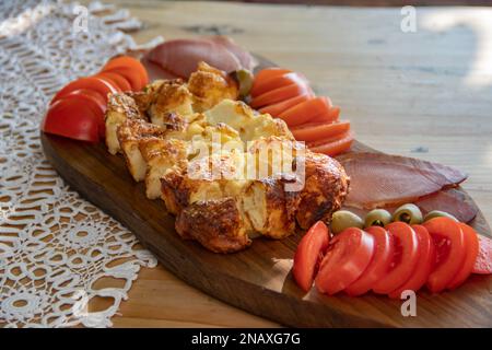 Serbian traditional food plate contain beef and pork smoked dried meet, cheese, vegetables and proja bread made of corn flour , served at wooden plate Stock Photo