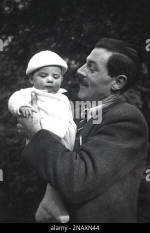 1950s, historical, outside, a father, wearing a woollen sports jacket and shirt & tie closely holding his infant son, who has a fancy little beret on his head, England, UK. Stock Photo