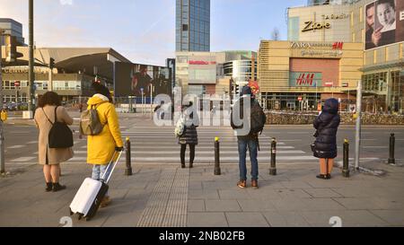 Warsaw, Poland. 10 February 2023. People of different ages crossing the road through. View of a city street with residents, tourists and modern buildi Stock Photo