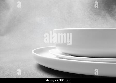 Stack of white porcelain plates and bowls on neutral gray background. copy space Stock Photo