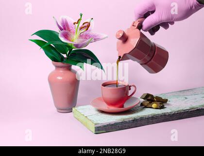 Coffee pouring into a pink cup with lily flower in a vase Stock Photo