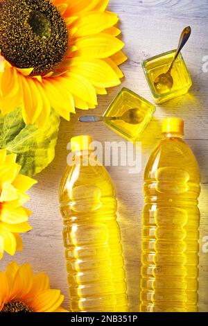 Plastic bottles with sunflower oil, fresh yellow sunflowers.Flat top view copy space.Composition with sunflower oil on white wooden table on white Stock Photo