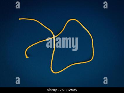 A bright colored thread located on a dark colored background. A single bright thread Stock Photo