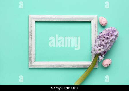 Composition with empty picture frame, hyacinth flower and Easter eggs on color background Stock Photo