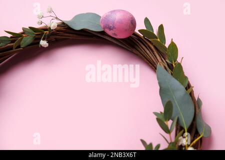 Easter wreath decorated with eggs and eucalyptus branches on color background, closeup Stock Photo