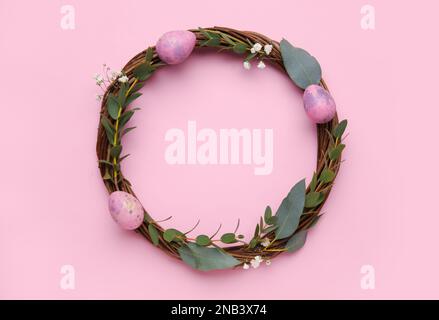 Easter wreath decorated with eggs and eucalyptus branches on color background Stock Photo