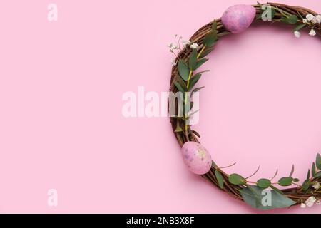 Easter wreath decorated with eggs and eucalyptus branches on color background Stock Photo