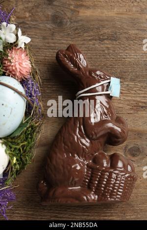 Chocolate bunny with protective mask on wooden table, top view. Easter holiday during COVID-19 quarantine Stock Photo