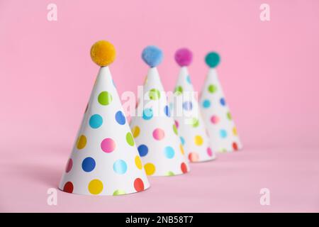 Colorful party hats with fluffy balls and blowers on pink background ...
