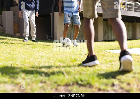Legs of diverse teenager male friends playing soccer in backyard. Hanging out with friends and spending quality time together concept. Stock Photo