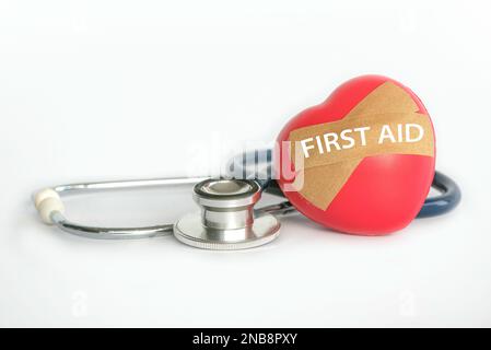 First aid concept with stethoscope and red heart or love with bandage written with First Aid. Stock Photo
