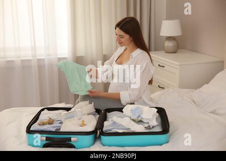 Pregnant woman packing suitcase for maternity hospital at home Stock Photo