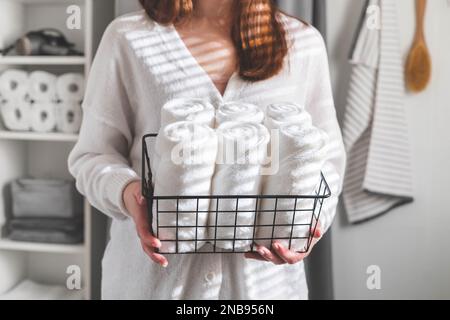 Woman's hands neatly putting or displaying a clean rolled up white towels made from organic cotton. Stock Photo