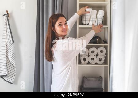 Woman's hands neatly putting or displaying a clean rolled up white towels made from organic cotton. Stock Photo