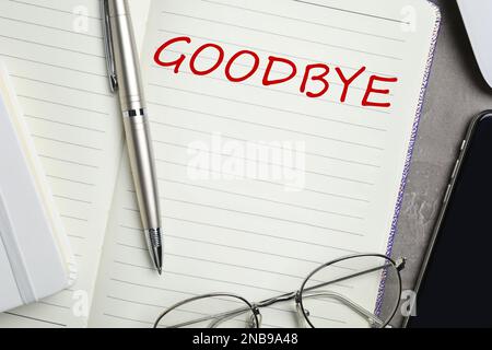 Notebook with word Goodbye, pen and glasses on table, closeup Stock Photo