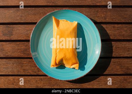 Hallaca or Tamale over a rustic table and a blue dish, Mexican and Venezuelan traditional food Stock Photo