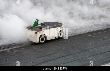 230212-N-WM182-1012 SOUTH CHINA SEA (Feb. 12, 2023) A U.S. Navy Sailor operates an aircraft tractor on the flight deck aboard the aircraft carrier USS Nimitz (CVN 68). Nimitz is in U.S. 7th Fleet conducting routine operations. 7th Fleet is the U.S. Navy's largest forward-deployed numbered fleet, and routinely interacts and operates with Allies and partners in preserving a free and open Indo-Pacific region. (U.S. Navy photo by Mass Communication Specialist 2nd Class Caitlin Flynn) Stock Photo