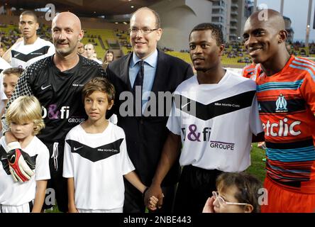 Prince Albert II of Monaco, poses with former goalkeeper Fabien Barthez of France, left, Manchester United player Patrice Evra, second from right, and Marseille player Charles Kabore before a charity match between Olympique Marseille soccer team and a Manchester United team Tuesday, Aug. 2, 2011, in Monaco stadium. (AP Photo/Lionel Cironneau)