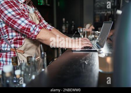 cropped shot of young barista taking notes and using laptop. Stock Photo