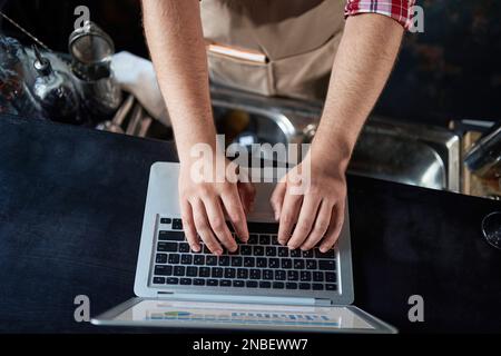 cropped image of a male bartender using a laptop. Stock Photo