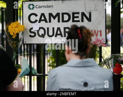 An unidentified woman looks at floral tributes left at an address sign near the residence of singer Amy Winehouse in Camden Square, north London, Sunday, July 24, 2011. Amy Winehouse, the beehived soul-jazz diva whose self-destructive habits overshadowed a distinctive musical talent, was found dead Saturday, July 23, 2011 in her London home. She was 27.(AP Photo/Akira Suemori)
