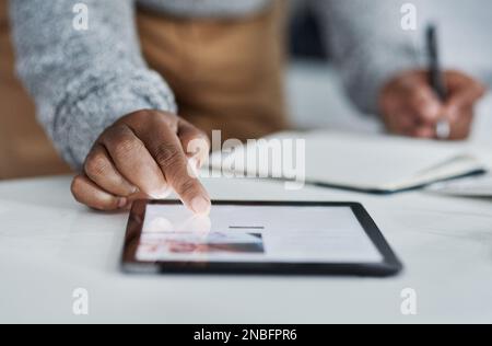 Multitasking is a skill learnt by many entrepreneurs. an unrecognizable businessman sitting alone in the office and using a tablet. Stock Photo
