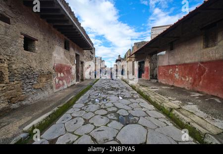 A perspective view, looking down the Via dell' Abbondanza street with various tourists. At Pompeii Archaeological Park near Naples, Italy. Stock Photo