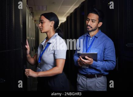 Engineer, server room teamwork and woman opening panel for maintenance or repairs at night. Cybersecurity, programmers and female with man holding Stock Photo