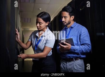 Engineer teamwork, server room and woman opening panel for maintenance or repairs at night. Cybersecurity, programmers and female with man holding Stock Photo