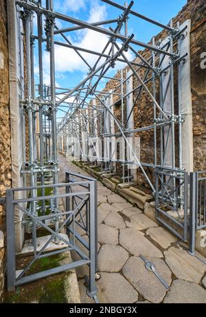 Preservation, restoration work with metal scaffolding being done along a cobblestone street. At Pompeii Archaeological Park near Naples, Italy. Stock Photo