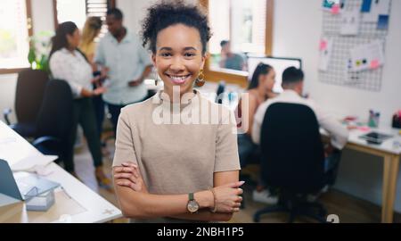 If you need it designed, our team will do it. Portrait of a confident young businesswoman working in a modern office with her team in the background. Stock Photo
