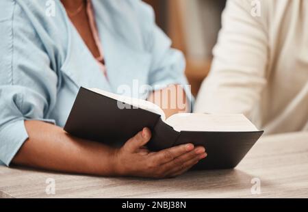 Hands, bible and books with a senior couple reading a book together in their home during retirement. Jesus, faith or belief with a man and woman Stock Photo