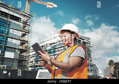 Making paper blueprints a thing of the past. a young woman using a digital tablet while working at a construction site. Stock Photo