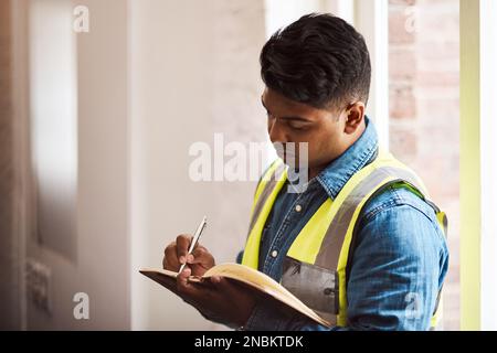 It takes careful planning to make a project a success. a engineer making notes while on a construction site. Stock Photo