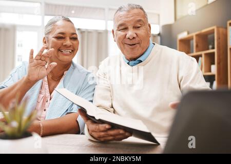Wave, laptop and senior couple on video call with book or bible for spiritual studying or reading in home. Greeting, retirement and elderly man and Stock Photo