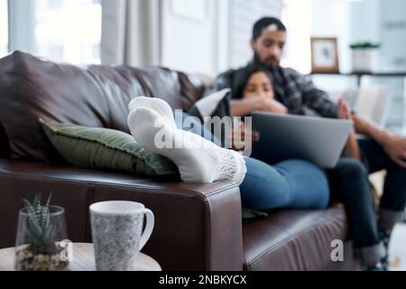 Immerse yourself in the warm embrace of of home. a young couple using a laptop while relaxing on the sofa at home. Stock Photo
