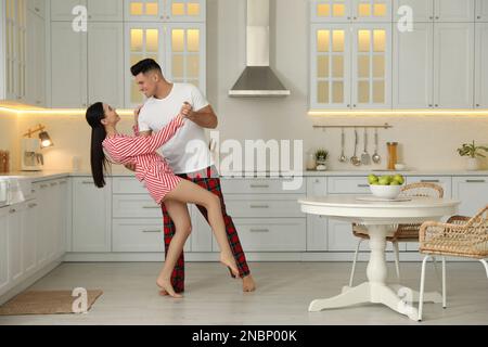Happy couple wearing pyjamas and dancing in kitchen Stock Photo