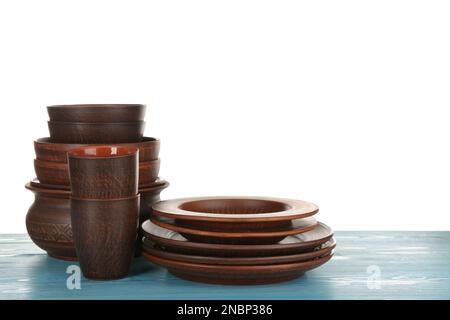 Different clay dishware on light blue wooden table against white background Stock Photo