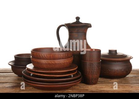 Different clay dishware on wooden table against white background Stock Photo