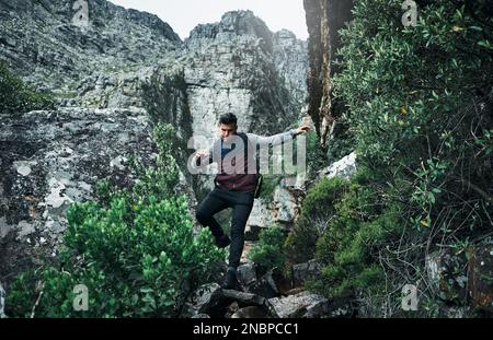 Its a rocky climb. a young man hiking through the mountains. Stock Photo