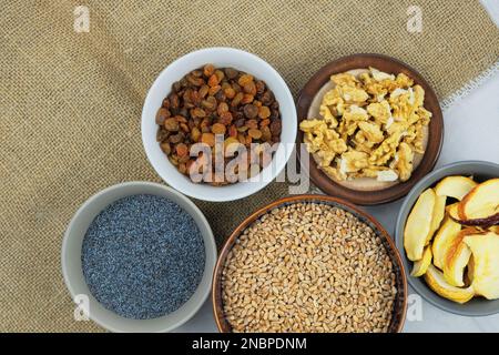 Wheat, raisins, poppy seeds, walnuts, dried apples. Ukrainian kutia ingredients in bowls. Stock Photo