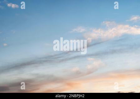 Sky at sunset with a gradient of color from warm to cold. Sky background with light stretched clouds in the sun. Stock Photo