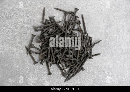 Bunch black wood screws gray background Stock Photo